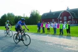 Cyclist rides past supporters at a fundraising bike event